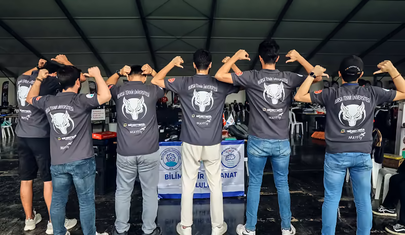BTÜ ÖZTÜRK takımı TEKNOFEST 2021'de, sırtları dönük; tişörtlerde üniversite, takım ve o dönemin sponsor logoları